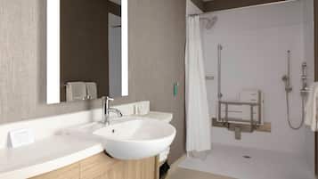 Une salle de bain moderne dotée d’un grand lavabo, d’un miroir et d’un espace douche.