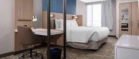 Een hotelkamer met een bed, bureau, stoel en een kledingkast.