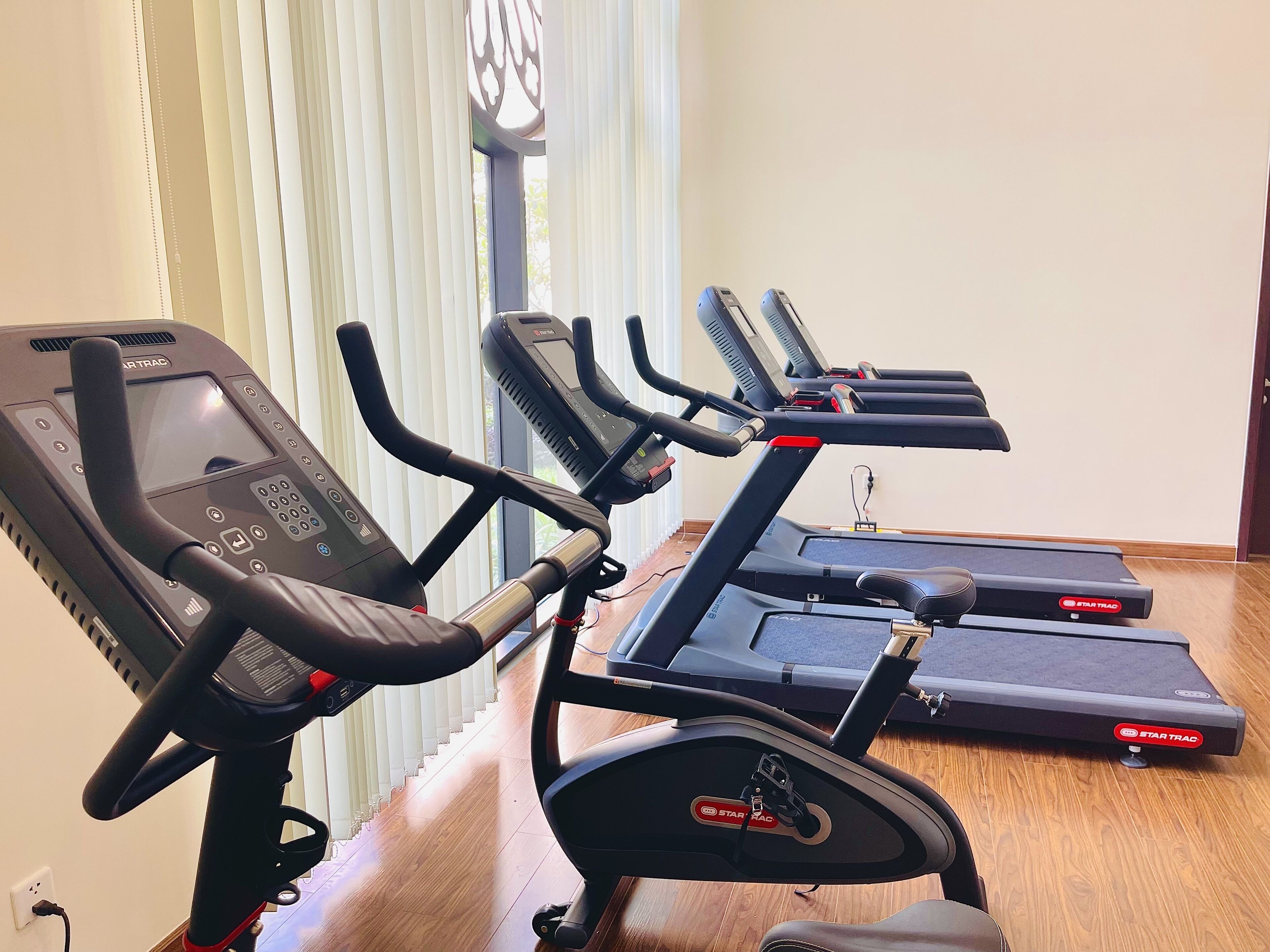 Ein Heimfitnessraum mit Laufband, Crosstrainer und stationärem Fahrrad, alles von STARTRAC.