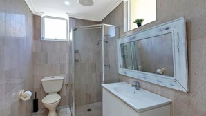 Een badkamer met toilet, wastafel, douche en een grote spiegel.