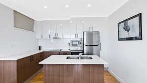 Een moderne keuken met witte kasten, een roestvrijstalen koelkast, een oven en een magnetron.