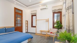 A bedroom with a bed, a chair, a small table, and a potted plant. - Chipa Homestay (Da Nang)