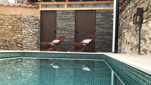 A swimming pool with tiled edges, two doors with stone walls, and wooden lounge chairs. - RURAL HOUSE LA CABEZUELA (El Real de San Vicente)
