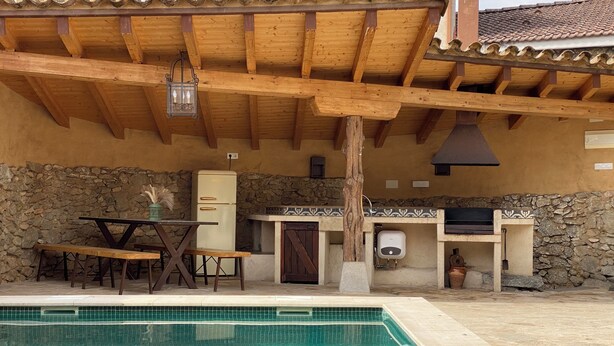 A poolside area with a wooden pergola, stone wall, and a small kitchen setup. - RURAL HOUSE LA CABEZUELA (El Real de San Vicente)