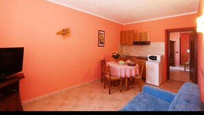 A compact living space with a dining area, kitchenette, and a television.