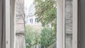 An open window with a view of a building with a dome and trees.