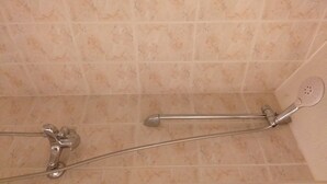 Un espace douche équipé d’un pommeau de douche à main et d’un flexible de douche.