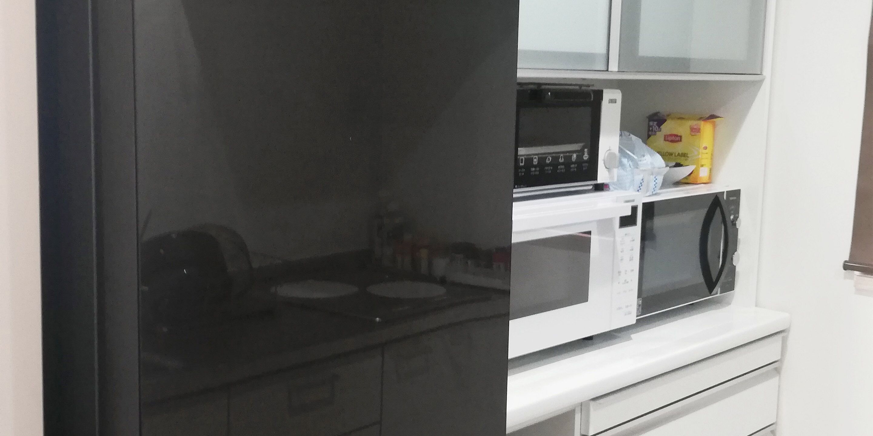 A kitchen with a microwave, a stove, and a shelf with a bag of chips.