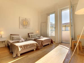 Habitación de hotel con dos camas, suelo de madera, una ventana grande y vistas al exterior.