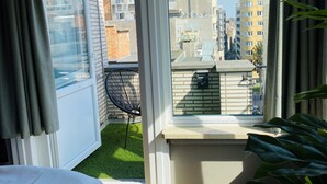 A room with a large window, a view of the city, a small balcony, and a potted plant. - Prado Next Door (Ostend)