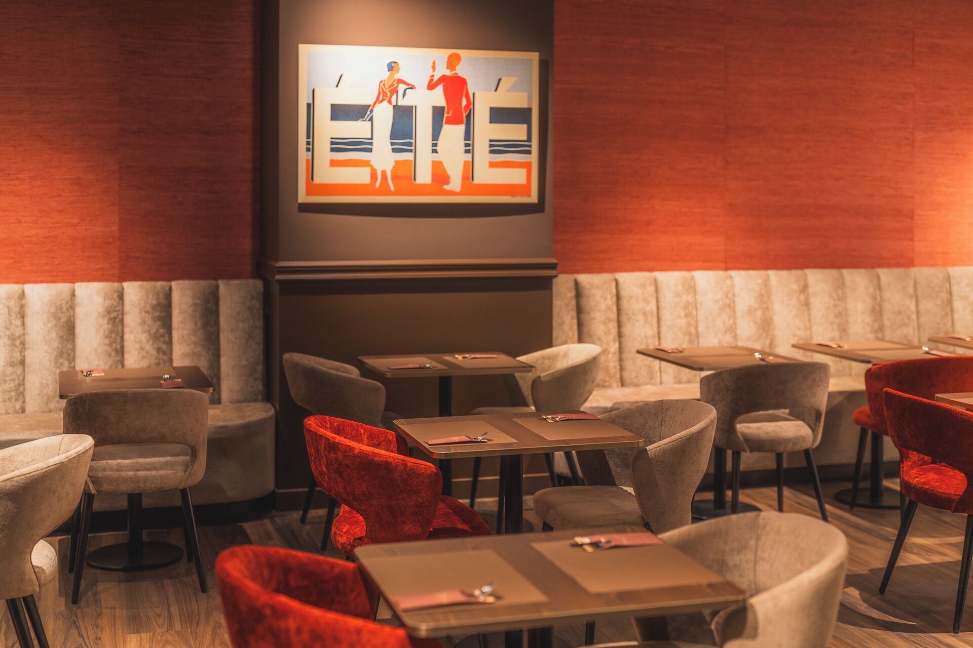 A restaurant with booths, tables, and red chairs.