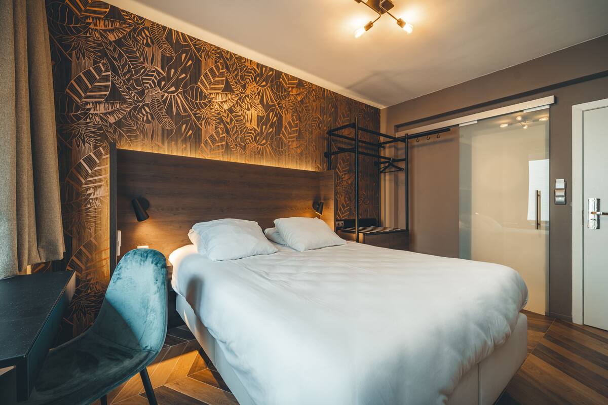Una habitación de hotel moderna con una cama grande, un escritorio y una silla.