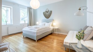 Een slaapkamer met een bed, nachtkastjes, een lamp en een raam.