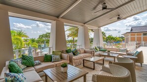 Un espace extérieur aménagé en terrasse, avec des canapés de couleur beige, des fauteuils en osier et une table en bois.