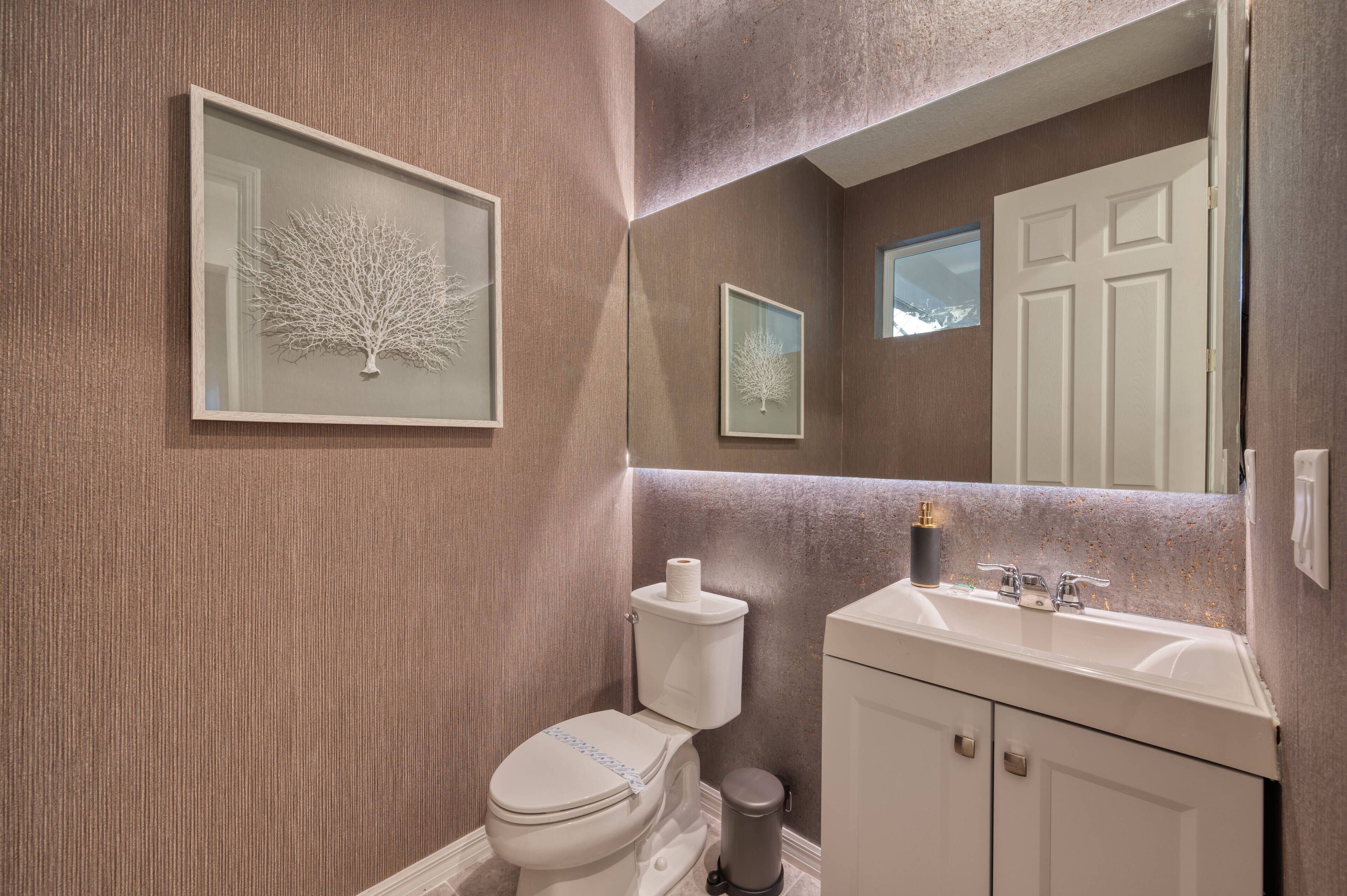 Ein Badezimmer mit Toilette, Waschbecken und einem gerahmten Kunstwerk an der Wand.