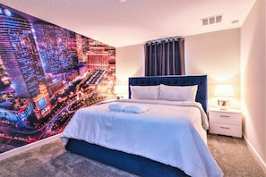 A hotel room with a large bed, a nightstand, a lamp, and a cityscape mural on the wall. - Gorgeous Brand New 7 Bedrooms House With Pool and Game Room at Champions Gate Resort (0730) (Kissimmee)