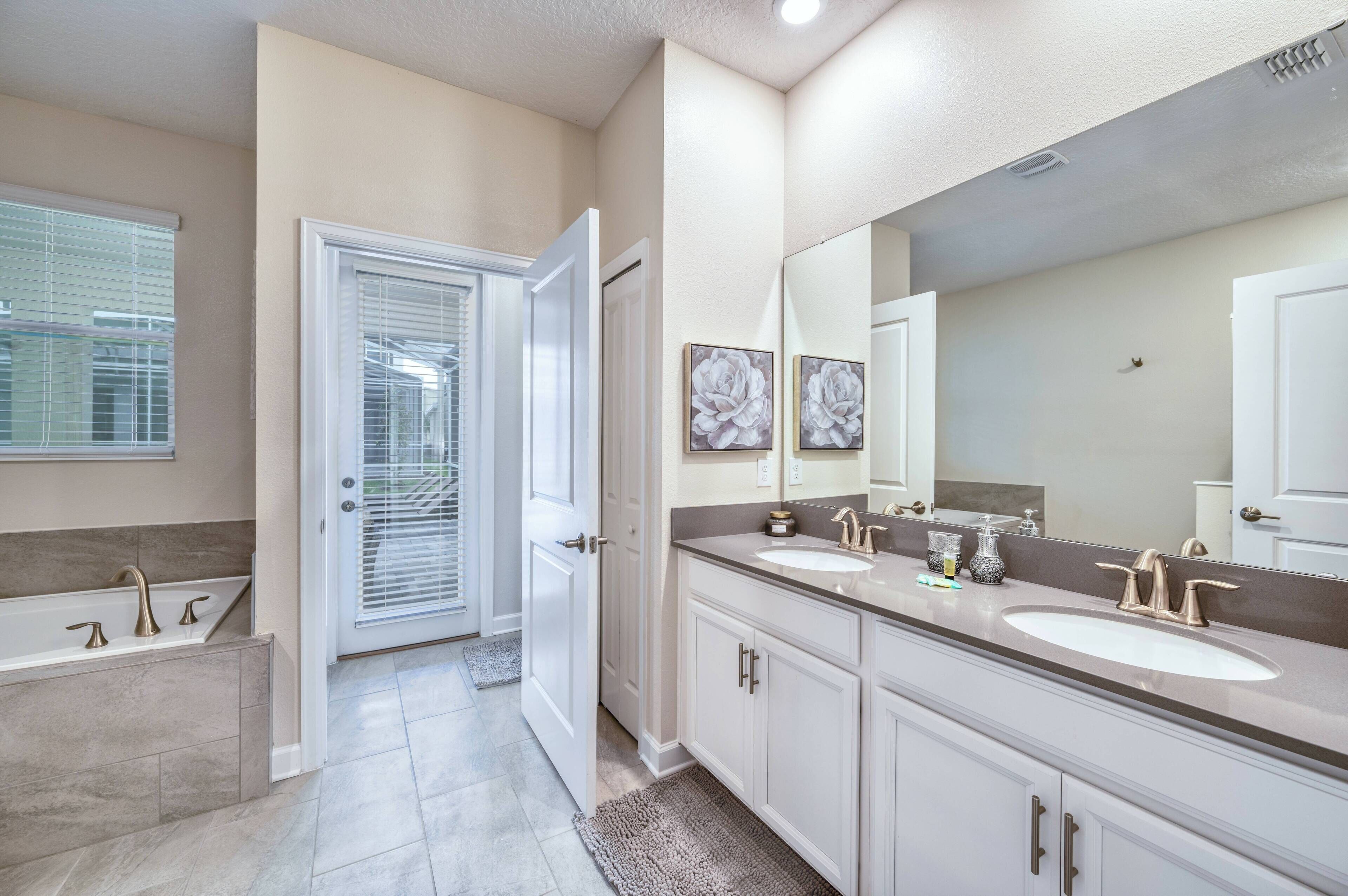 A modern bathroom with two sinks, a large mirror, and a bathtub.
