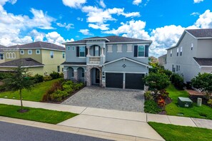 A two-story house with a front garage, a balcony, and a well-maintained lawn.