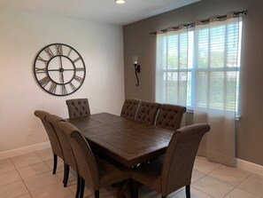 A dining room with a wooden table and six upholstered chairs.