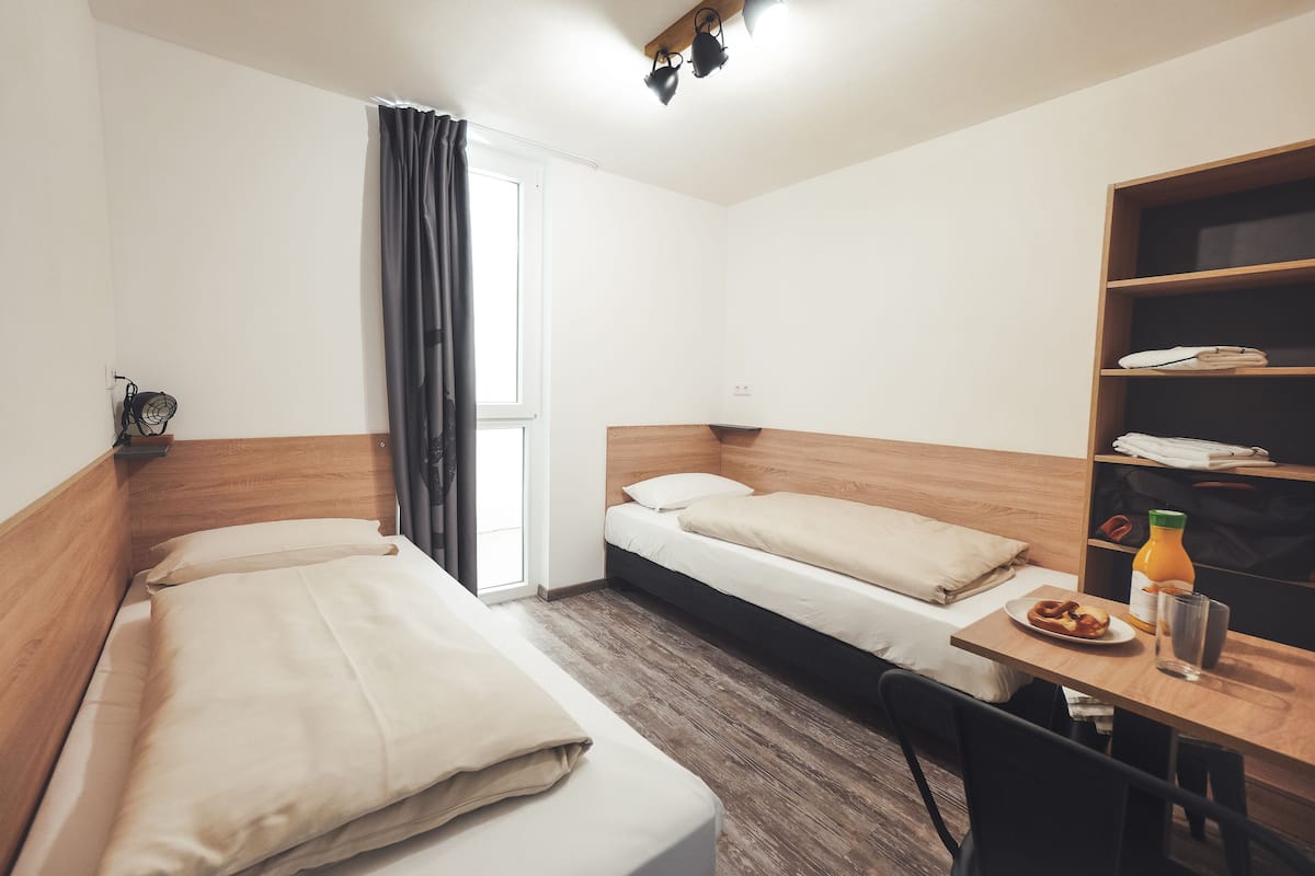 Une chambre avec deux lits, un bureau et une bibliothèque.