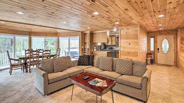 A cozy cabin interior with a wooden ceiling, a living area with a sofa and coffee table, a dining area with chairs, and a kitchen with wooden cabinets. - Raven Rock - 31 Acres, HOT TUB, Stream, fire Pit, Private, High Speed Internet (Henderson County)