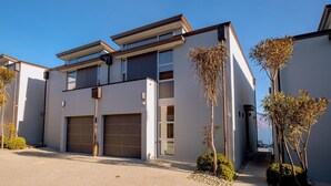 Un immeuble résidentiel moderne à deux étages, doté d’un garage, d’un balcon et offrant une vue dégagée sur le ciel.