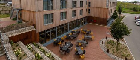 A hotel with a modern wooden facade, outdoor seating area, and a landscaped garden.