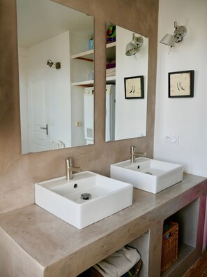 A bathroom with two white sinks, a large mirror, and a wall-mounted light fixture.
