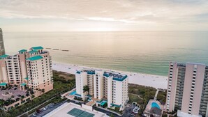A coastal hotel with multiple high-rise buildings, a beachfront promenade, and a pool area.