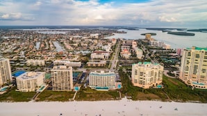 A coastal cityscape with high-rise buildings, a beach, and water bodies.