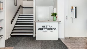 A reception desk labeled "Hestra Guesthouse" with a staircase leading to an upper floor.