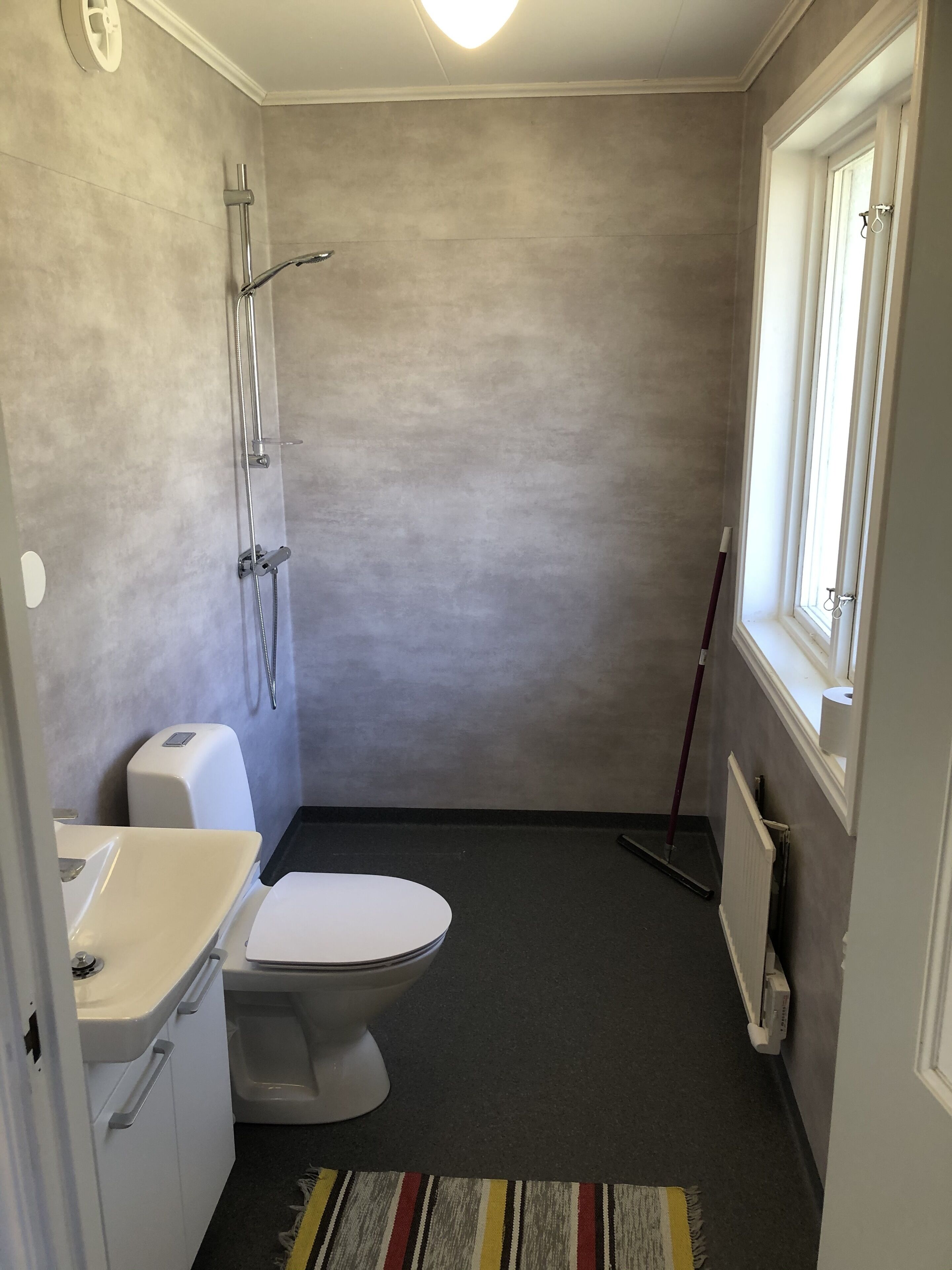 Une petite salle de bain compacte, équipée de toilettes, d’un lavabo et d’une douche.