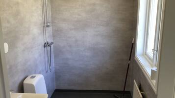 Une petite salle de bain compacte, équipée de toilettes, d’un lavabo et d’une douche.