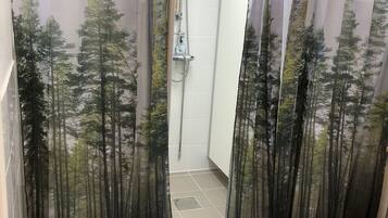 Un baño con ducha, piso de baldosas y cortinas de baño con motivos forestales.