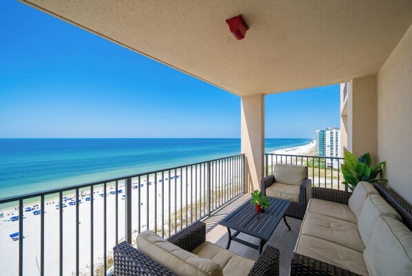A balcony with a view of the beach and ocean.