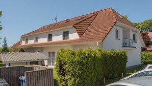 A two-story house with a red-tiled roof, white exterior walls, and a small balcony on the second floor. - Apartment in Prerow up to 2 p. + child up to 6 y., quiet, close to the beach, parking lot, WLAN (Prerow)