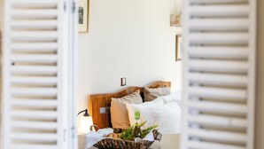 A bedroom with a bed, a bedside table, a lamp, and a mirror with shutters.