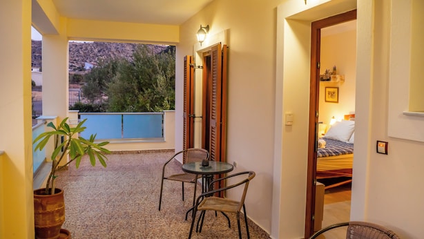 A corridor with a small table and chairs, a potted plant, and a view of a mountain and trees.