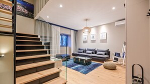 Una sala de estar moderna con una escalera, un juego de sofá, una mesa de centro y un ventanal grande.