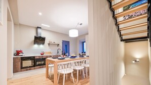 Una cocina moderna con suelo de madera, una mesa de comedor con sillas y una escalera con barandilla decorativa.