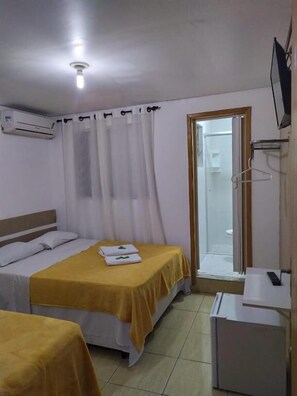 A hotel room with two beds, an air conditioning unit, a shower area, and a television. - Hospedaria Integração Ipiranga (São Paulo)