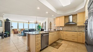 A modern kitchen with a central island, built-in appliances, and a dining area with a view. - Three Bedroom Condo with Lazy River & Gulf of Mexico Views. Complimentary Boat Slip! (Orange Beach)