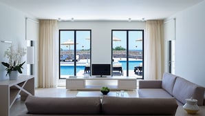 Una sala de estar moderna con un gran ventanal, un televisor de pantalla plana, un sofá y una mesa de centro.