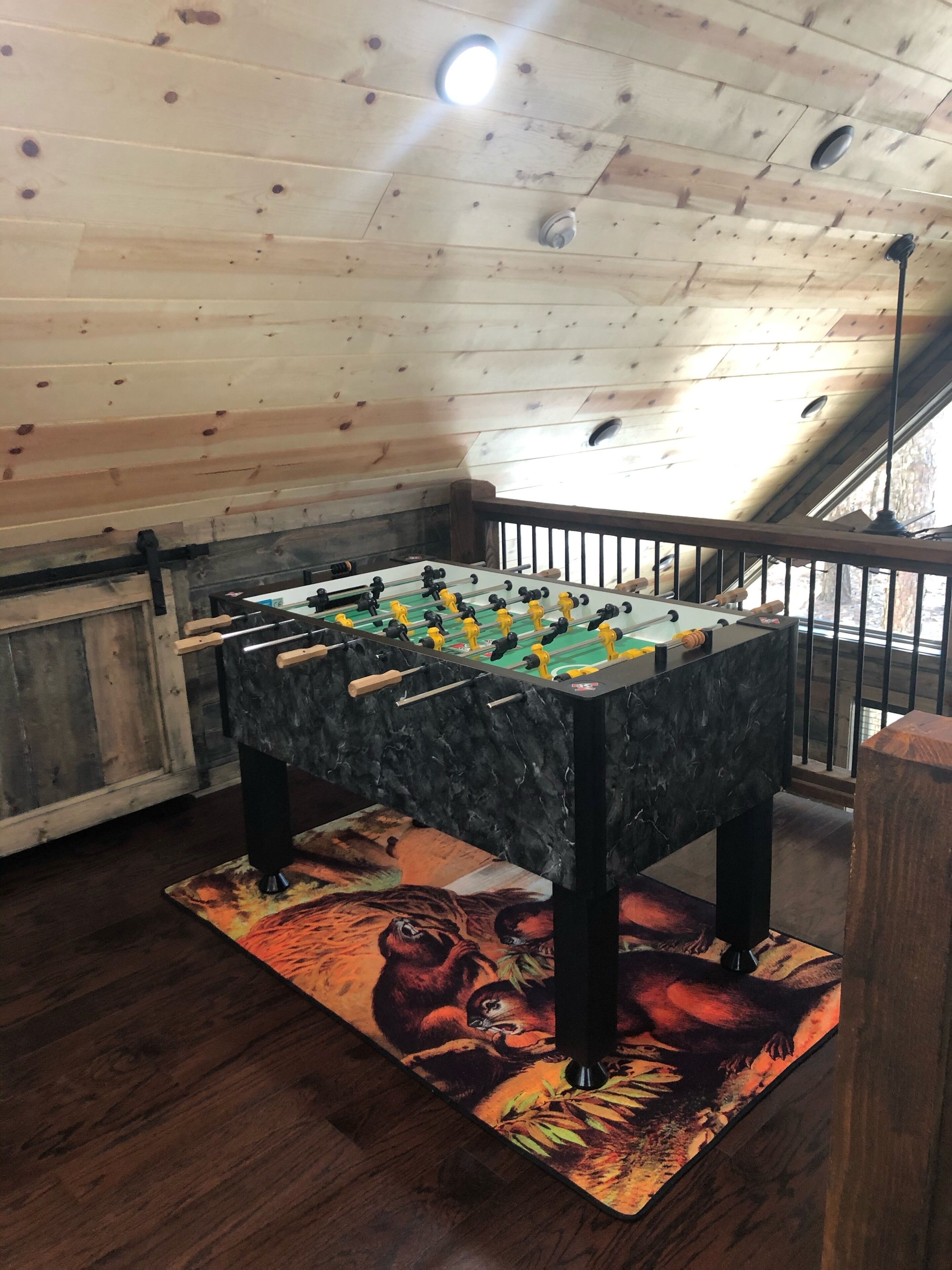 A foosball table in a room with wooden walls and a wooden floor.