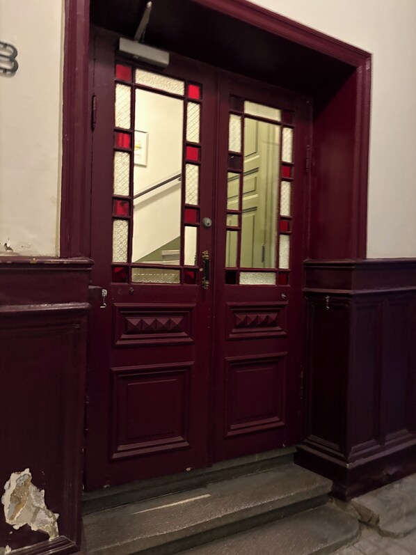 A dark red wooden door with glass panels and a small step leading up to it.