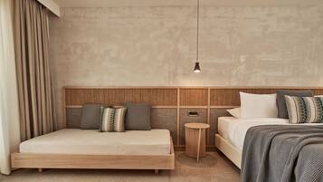 Una habitación de hotel moderna con una cama grande, una cama más pequeña, una mesita redonda y una lámpara colgante.