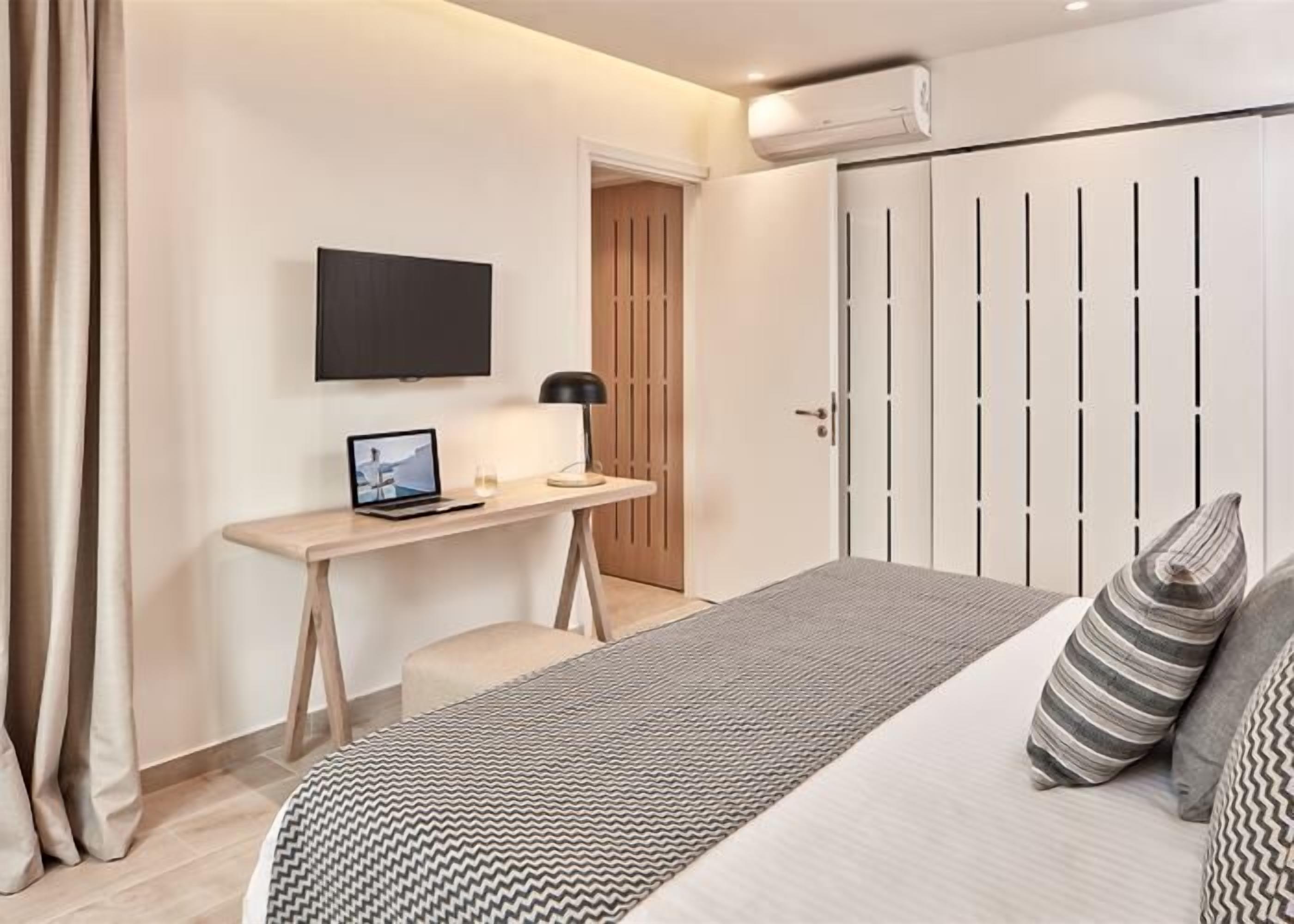 A bedroom with a bed, a desk, a TV, and a wardrobe.