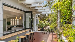 Una cocina moderna con un ventanal grande, mostrador de bar de madera y taburetes.