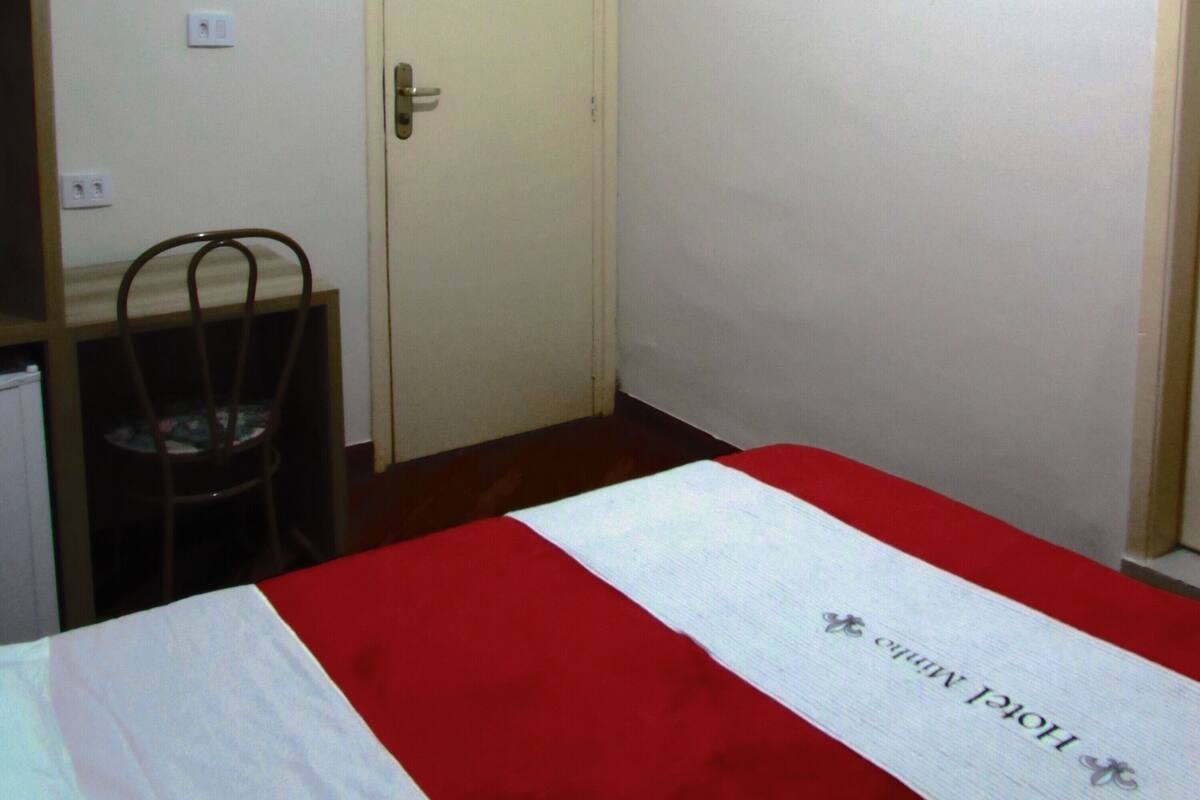Una habitación de hotel con cama, una silla, un escritorio y una puerta.