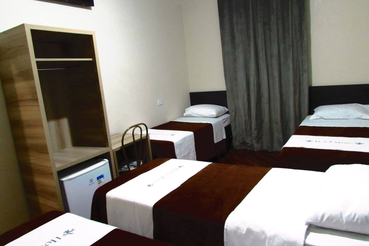 Una habitación de hotel con dos camas, un armario y un televisor.